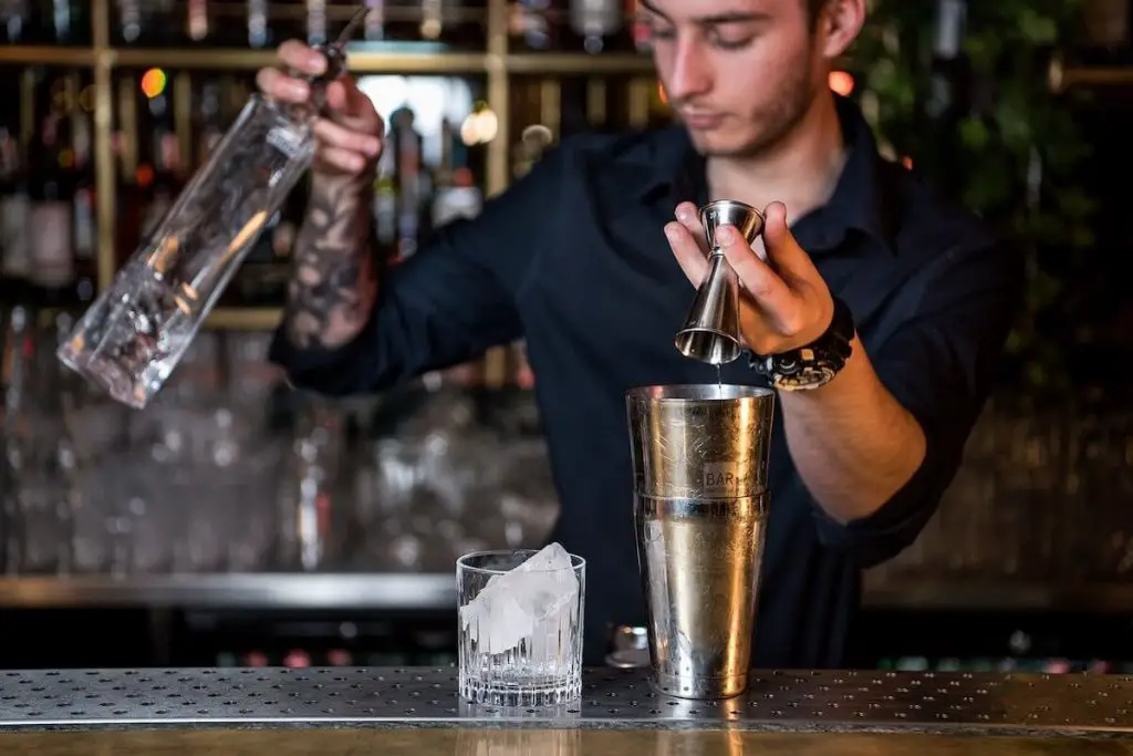 Bartender using a jigger; one of the essential bartending tools for beginners.