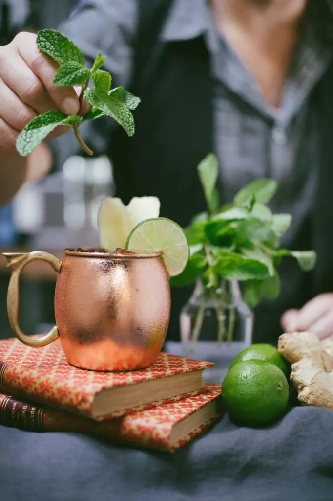 Bartender topping-off a moscow mule with mint garnish.