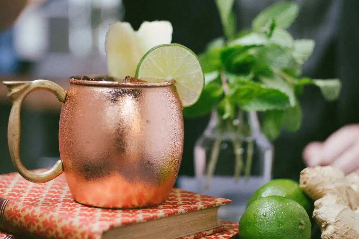Bartender topping-off a moscow mule with mint garnish.