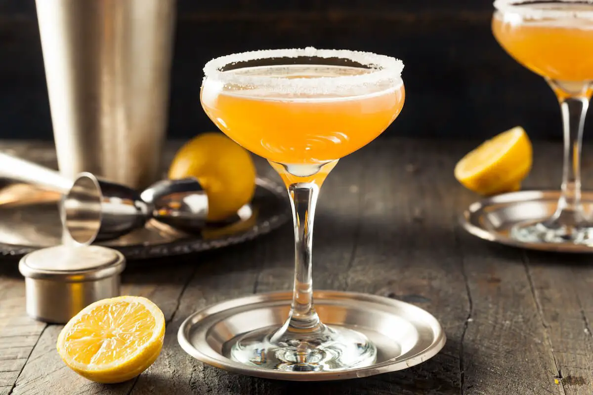Sidecar cocktail in coupe glass with lemon and shaker