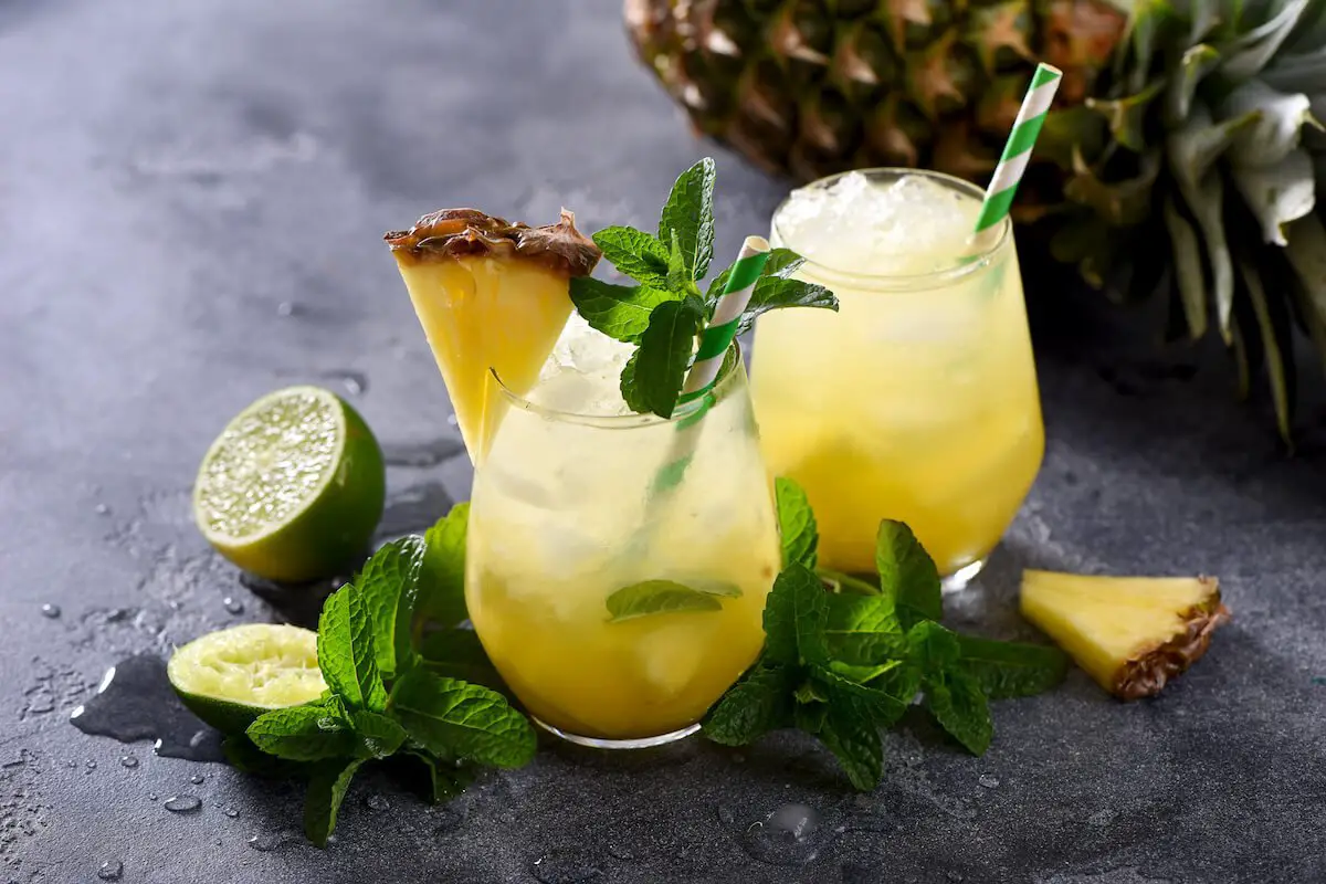 The democrat cocktail drink in a lowball glass with pineapple and mint garnish
